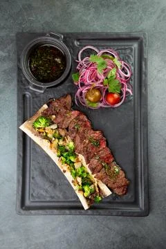 Beef steak with sugar bone, served with sauce and salad of onions, pomilors and Stock Photos