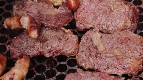 Beef steaks and sausages being turned with a large fork on a hot grill 스톡 동영상 337941086