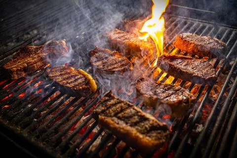 Beef steaks on the grill with flames. Stock Photos