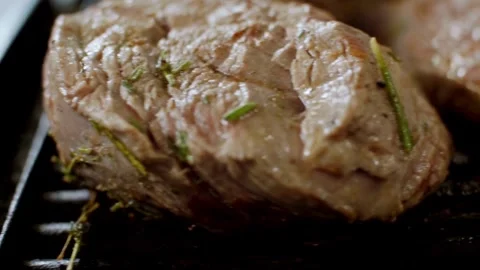 Beef steaks grilling with herbs on a hot pan Stock Footage 333830956