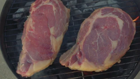 Beef steaks roasting on a brazier. Two ribeye steaks slowly roast on a grill Stock Footage 285469171