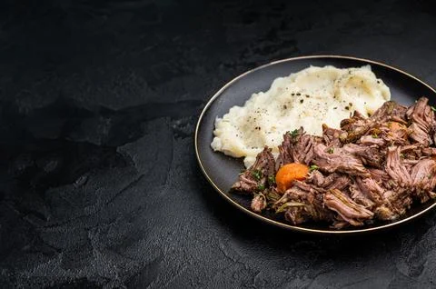 Beef stew with mashed potatoes, carrots and herbs on a plate isolated. blac.. Stock Photos