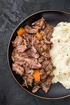 Beef stew with mashed potatoes, carrots and herbs on a plate isolated. blac.. Stock Photos