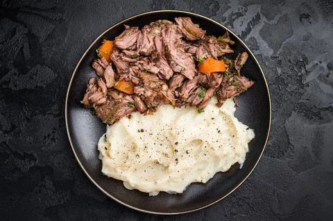 Beef stew with mashed potatoes, carrots and herbs on a plate isolated. blac.. Stock Photos