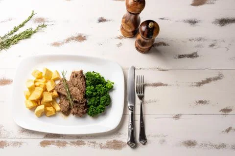 Beef stew with rustic potato and broccoli in a white plate on white wooden ta Stock Photos