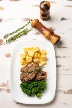 Beef stew with rustic potato and broccoli in a white plate on white wooden ta Stock Photos