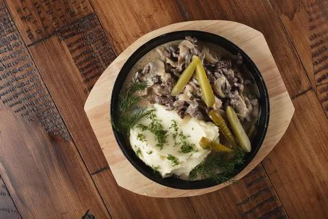 Beef stroganoff with mushed potatoes and pickled cucumbers Stock Photos
