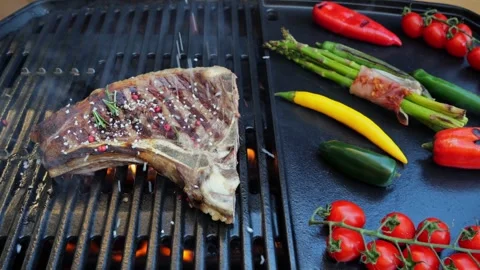 Beef T-Bone steak on grill sprinkle spices, grilled vegetables. Slow motion. Stock Footage 271137415