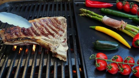 Beef T-Bone steak  grill turnover on barbecue, grilled vegetables. Slow motion. Stock Footage 271137432