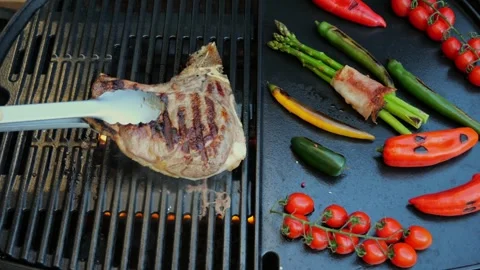 Beef T-Bone steak  grill turn over on barbecue, grilled vegetables. Slow motion. Stock Footage 272150938