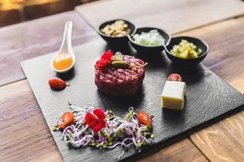 Beef tartar with raw egg and vegetables on a stone plate. High angle shot Stock Photos