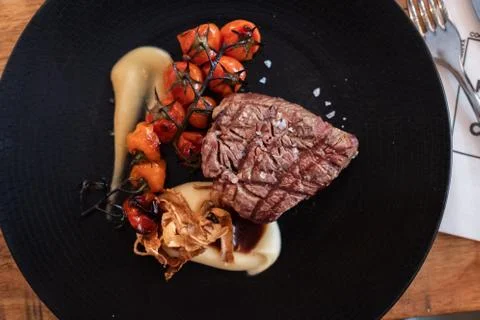 Beef tenderloin with rustic mashed potatoes, roasted cherrys and confit garli Stock Photos