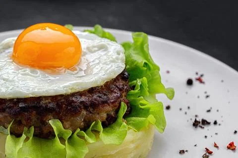 Beefsteak with egg and mashed potatoes on a dark background Stock Photos