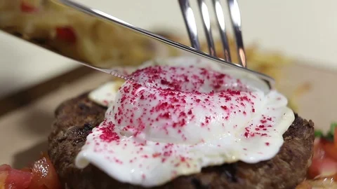 Beefsteak. Veal with poached egg.The client cuts the yolk of the egg with a k Stock Footage 98112488
