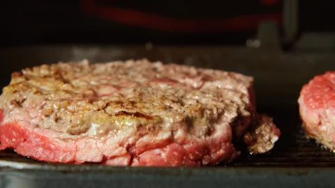 Beefsteaks frying on a grill - front view Stock Photos