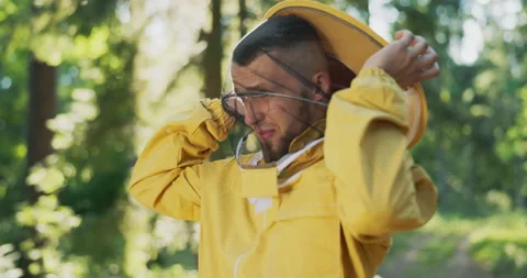A beekeeper gets ready for work in the forest at the apiary with bees, hives, he Stockbeeldmateriaal 165003434