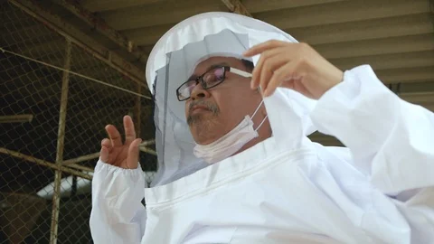 Beekeeper man in a white protective suit is harvesting with honeycomb in farm. Stock Footage 129640584