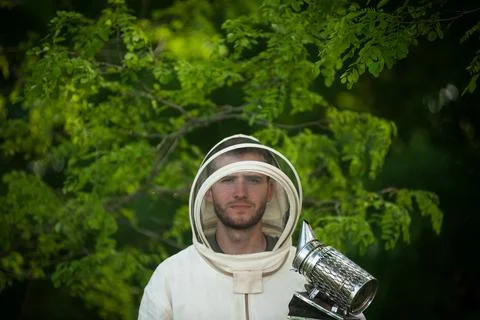 Beekeeper in a protective suit with smoke tool Stock Photos