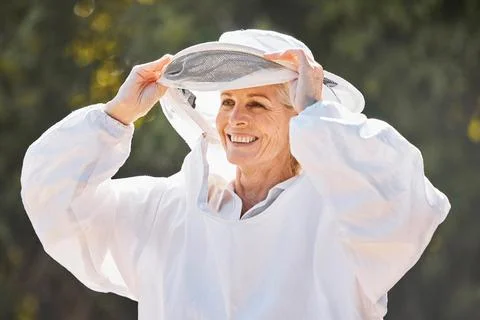 Beekeeper, safety suit and senior farm worker woman ready for honey, bee and Stock Photos