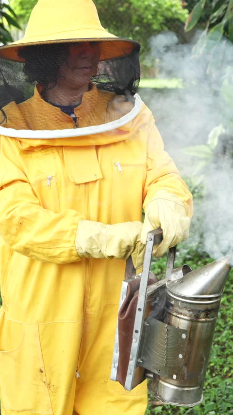 Beekeeper Using Smoker in Lush Garden in Vertical Format Stock Footage 328618288