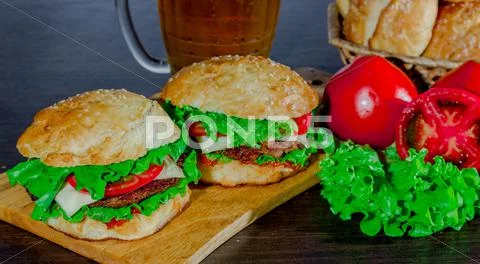 Beer and homemade burgers buns with beef patties fresh salad ingredients Stock Photos