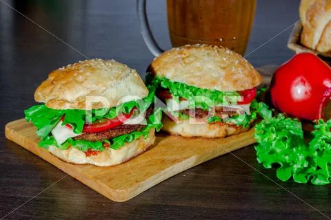 Beer and homemade burgers buns with beef patties fresh salad ingredients Stock Photos