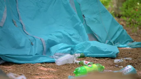 Beer and plastic bottles left next to abandoned tent at a camp site Stock Footage 132336087