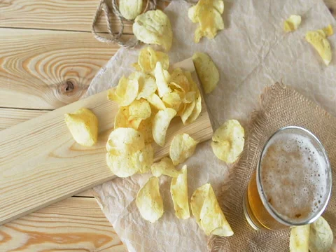 Beer and potato chips on the table. Theme Oktoberfest. Slow motion. woman takes Stock Footage 80565925