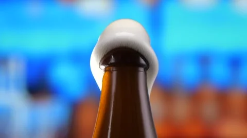 Beer in a beer bottle, forming bubbles and a frothy head. Beer foam flows down Stock Footage 280071747