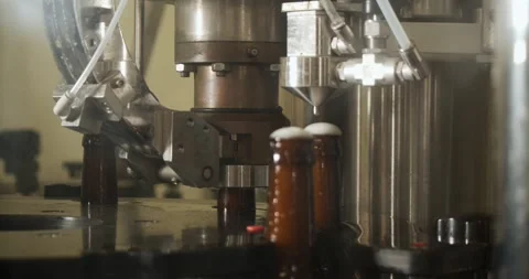 Beer bottle being closed with crown cap on automated line in brewery Stock Footage 335143248