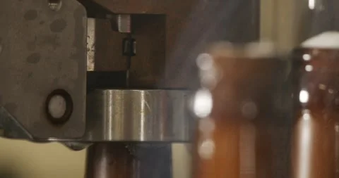 Beer bottle being closed with crown cap on automated line in brewery Video stock 335143396