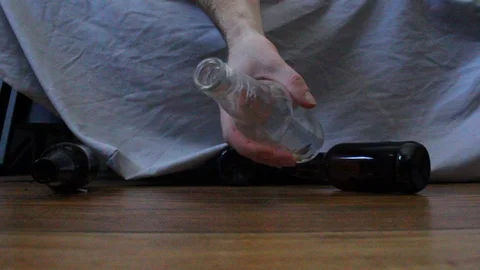 Beer bottle drops and rolls away from a drunk man who is sleeping Stock Footage 105000673