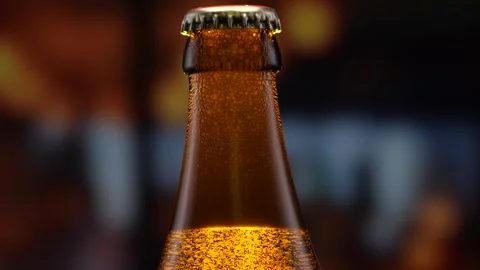 Beer bottle featuring lively bubbles and frothy foam, bar counter in background Stock Footage 257490206