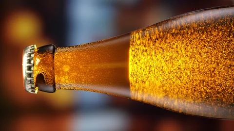 Beer bottle featuring lively bubbles and frothy foam, bar counter in background Stock Footage 257490249