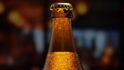 Beer bottle featuring lively bubbles and frothy foam, bar counter in background Stock Footage 258980187