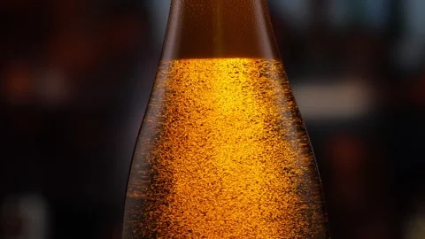 Beer bottle featuring lively bubbles and frothy foam, bar counter in background Stock Footage 258980235