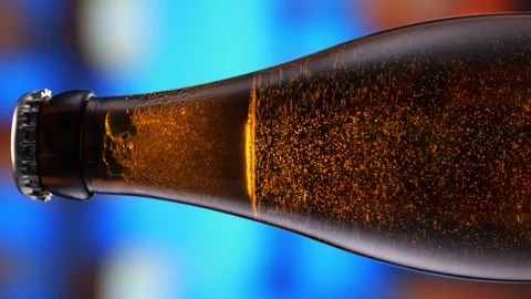 Beer bottle featuring lively bubbles and frothy foam, bar counter in background Stock Footage 259382790