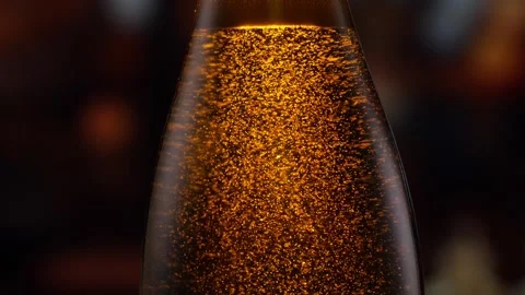 Beer bottle featuring lively bubbles and frothy foam, bar counter in background Stock Footage 259866964