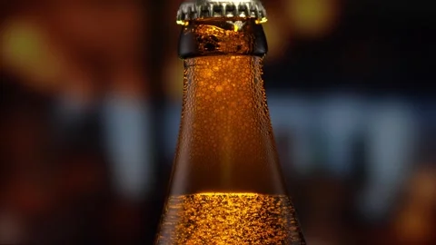 Beer bottle featuring lively bubbles and frothy foam, bar counter in background Stock Footage 261801330