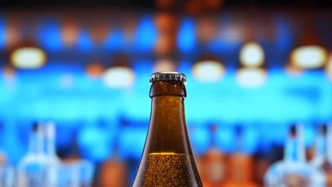 Beer bottle featuring lively bubbles and frothy foam, bar counter in background Stock Footage 263714598