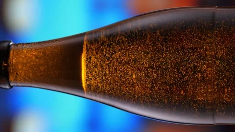 Beer bottle featuring lively bubbles and frothy foam, bar counter in background Stock Footage 275351731