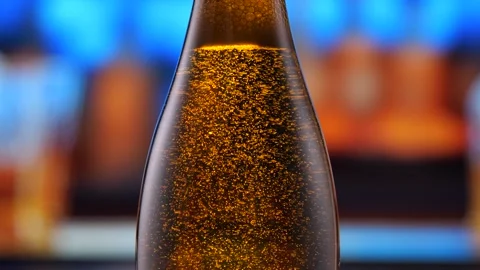 Beer bottle featuring lively bubbles and frothy foam, bar counter in background Stock Footage 276349497