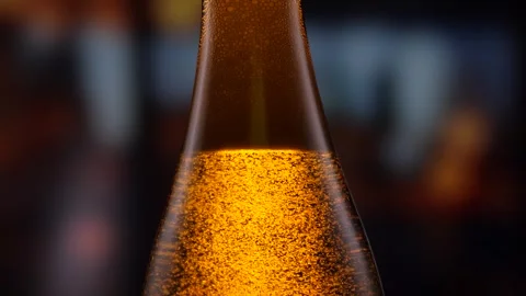 Beer bottle featuring lively bubbles and frothy foam, bar counter in background Stock Footage 278597272