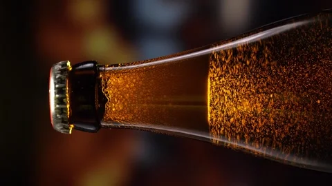 Beer bottle featuring lively bubbles and frothy foam, bar counter in background Stock Footage 278597328