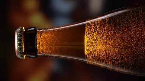 Beer bottle featuring lively bubbles and frothy foam, bar counter in background Video stock 279485832