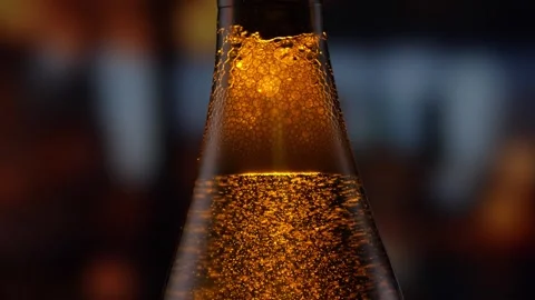 Beer bottle featuring lively bubbles and frothy foam, bar counter in background Stock Footage 280071817