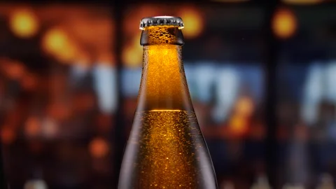 Beer bottle featuring lively bubbles and frothy foam, bar counter in background Stock Footage 282209058