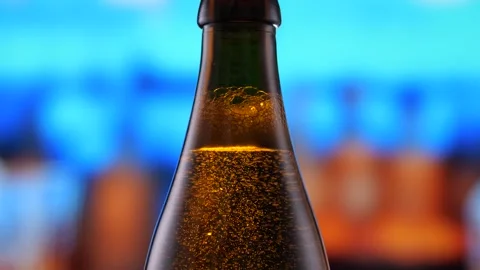 Beer bottle featuring lively bubbles and frothy foam, bar counter in background Stock Footage 282209135