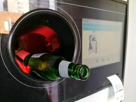 Beer bottle inserted in the automatic reverse vending machine for recycling Stock Photos