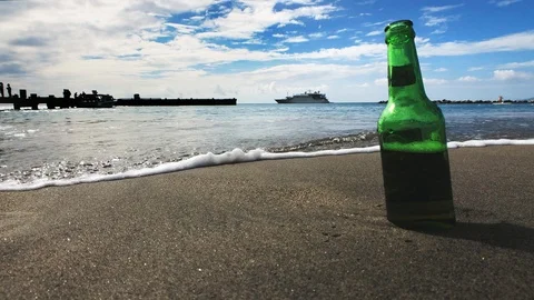 Beer bottle on sandy beach as water approaches Stock Footage 87859877